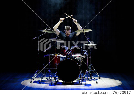 Drummer playing the drums with smoke and powder in the background. 76370917