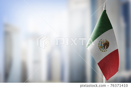 A small flag of Mexico on the background of a blurred background 76371410