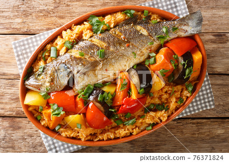 Senegalese Thieboudienne it is a preparation of fresh fish, and rice, cooked with vegetables such as cassava, pumpkin, cabbage, carrot, eggplant closeup. horizontal top view Senegalese Thieboudienne it is a preparation of fresh fish, and rice, cooked with vegetables such as cassava, pumpkin, cabbage, carrot, eggplant closeup. horizontal top view 76371824