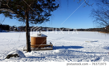 The sauna cabin is ready by the frozen lake 76371973