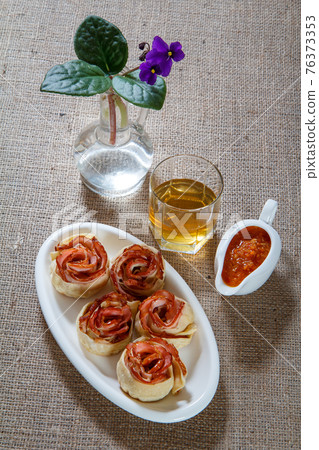 Homemade pastry with ham in the form of rose on white plate Homemade pastry with ham in the form of rose on white plate 76373353