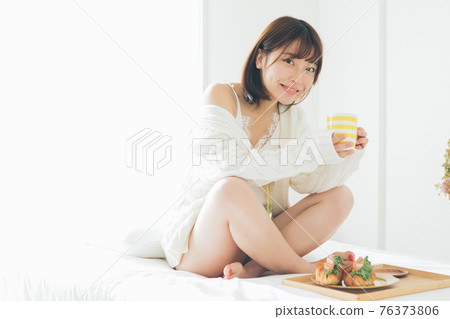 A woman drinking coffee on the bed 76373806