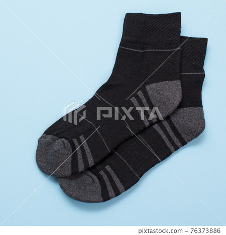 Pair of black woolen men socks on blue background. Pair of black woolen men socks on blue background. 76373886