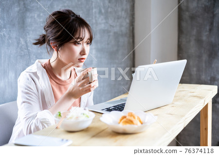 Young woman using a laptop for breakfast Young woman using a laptop for breakfast 76374118