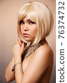beauty portrait of a young beautiful blonde girl of Asian or Egyptian appearance on a pink solid background. 76374732