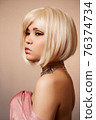 beauty portrait of a young beautiful blonde girl of Asian or Egyptian appearance on a pink solid background. 76374734
