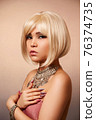 beauty portrait of a young beautiful blonde girl of Asian or Egyptian appearance on a pink solid background. 76374735