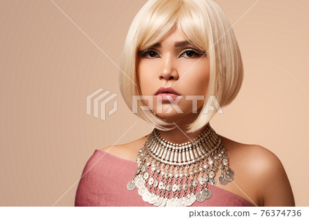 beauty portrait of a young beautiful blonde girl of Asian or Egyptian appearance on a pink solid background. 76374736