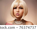 beauty portrait of a young beautiful blonde girl of Asian or Egyptian appearance on a pink solid background. 76374737