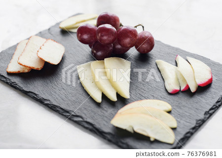 gourmet mixed cheese board tapas starter with apple and grapes 76376981