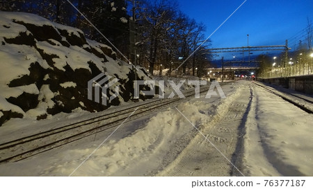 A perspective of the rails of a train station at dawn in northern Europe 76377187
