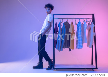 African american young guy standing near clothes hangers 76377201