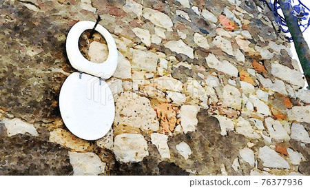 The white lid of a toilet hanging on a wall on the street in a small town. Digital color painting. The white lid of a toilet hanging on a wall on the street in a small town. Digital color painting. 76377936
