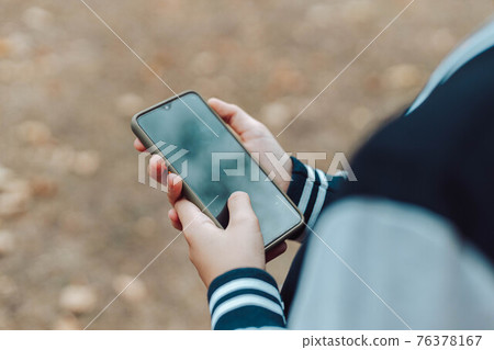 Child hands uses smartphone in summer park or garden outside. Child hands uses smartphone in summer park or garden outside. 76378167