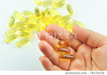 Woman hand with fish oil capsule. Vitamins. Woman hand with fish oil capsule. Vitamins. 76378316
