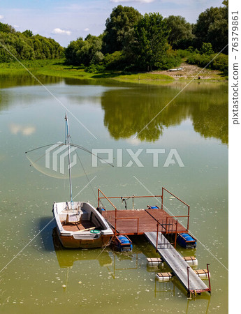Green lagoon and woods with dock and boat in the italian countryside  76379861