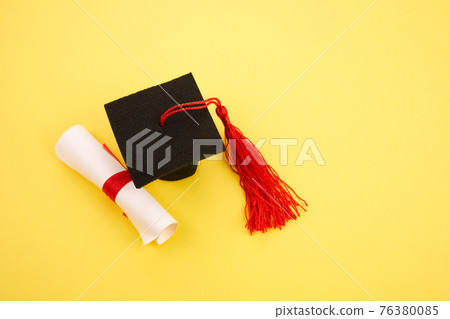 Academic hat with diploma on yellow background. Graduation theme Academic hat with diploma on yellow background. Graduation theme 76380085