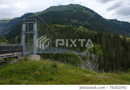 high suspension bridge between mountains trees and rocks 76382042