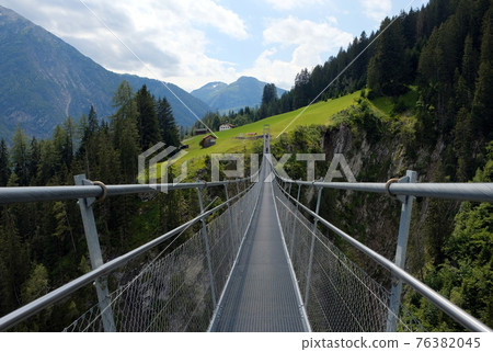 high suspension bridge between mountains trees and rocks high suspension bridge between mountains trees and rocks 76382045