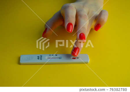 coronavirus test on a yellow, bright background. medical analysis. a girl with a bright red manicure puts her ring finger to perform the procedure 76382780