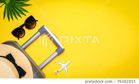 Sea shells. Suitcase, sunglasses with palm leaves and straw hat, white plane in travel composition on yellow background. Road frame set. Flat lay, top view. 76382855