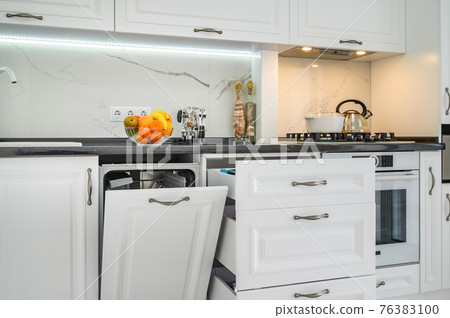 Luxurious white modern kitchen interior, drawers pulled out, dishwasher's door open Luxurious white modern kitchen interior, drawers pulled out, dishwasher's door open 76383100