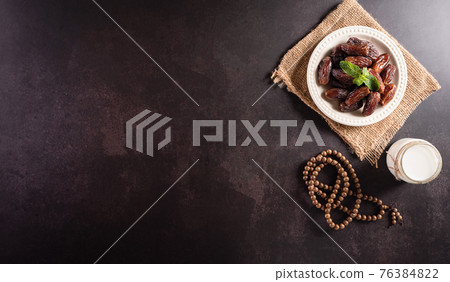 Table top view image of decoration Ramadan Kareem, dates fruit, . milk, and wood rosary on dark stone background. Flat lay with copy space. 76384822