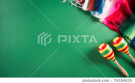 Cinco de Mayo holiday background made from maracas, mexican blanket stripes or poncho serape on green background. 76384829