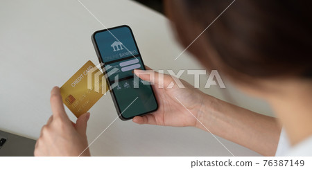 Close up hand of woman making card payment through mobile phone to pay bills 76387149