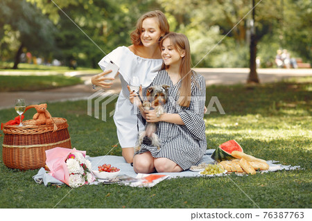 Two cute girls in a park playing with little dog Two cute girls in a park playing with little dog 76387763