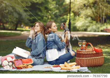 Two cute girls in a park playing with little dog 76387790