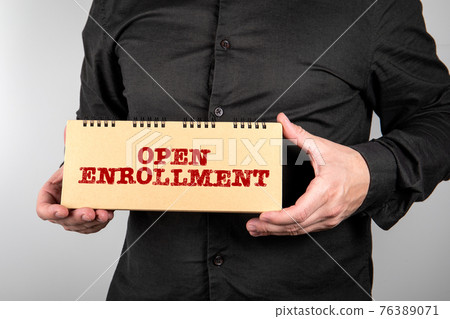 Open Enrollment. Business man with notepad on a light background Open Enrollment. Business man with notepad on a light background 76389071