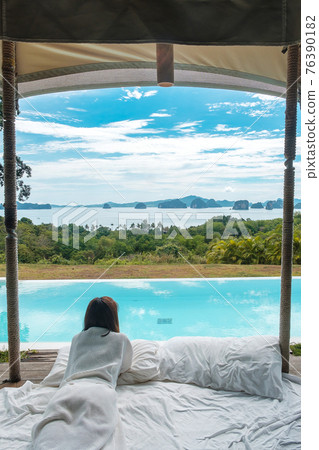 Happy woman traveler enjoy Beautiful ocean view, Tourist relaxing in tropical luxury resort with swimming pool. Leisure, travel and summer vacation concept Happy woman traveler enjoy Beautiful ocean view, Tourist relaxing in tropical luxury resort with swimming pool. Leisure, travel and summer vacation concept 76390182