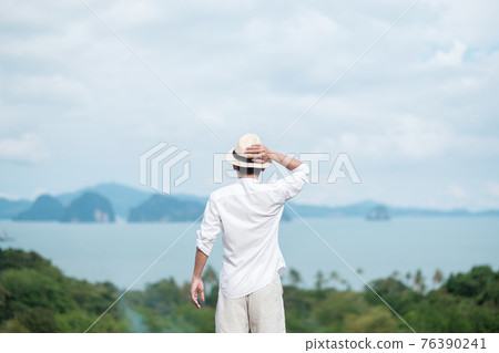 Happy traveler man in white shirt enjoy Beautiful view, alone Tourist with hat standing and relaxing over ocean. travel, summer and vacation concept Happy traveler man in white shirt enjoy Beautiful view, alone Tourist with hat standing and relaxing over ocean. travel, summer and vacation concept 76390241