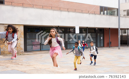 Happy tween schoolchildren with backpacks running to school outdoors Happy tween schoolchildren with backpacks running to school outdoors 76392143