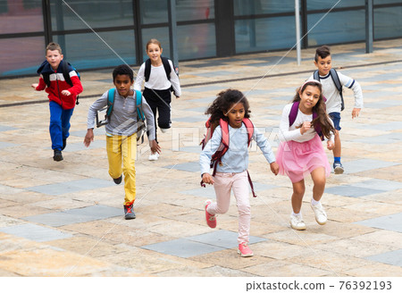 Happy tween schoolchildren with backpacks running to school outdoors Happy tween schoolchildren with backpacks running to school outdoors 76392193