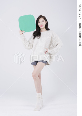 Asian female model with long hair holding copyspace poster, winter beauty promotion concept Asian female model with long hair holding copyspace poster, winter beauty promotion concept 76393050