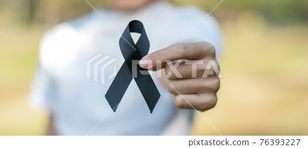 Melanoma and skin cancer, Vaccine injury awareness month and rest in peace concepts. Woman holding black Ribbon Melanoma and skin cancer, Vaccine injury awareness month and rest in peace concepts. Woman holding black Ribbon 76393227