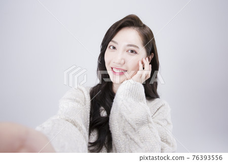 Asian female model with long hair taking selfie with smart phone, winter beauty concept Asian female model with long hair taking selfie with smart phone, winter beauty concept 76393556