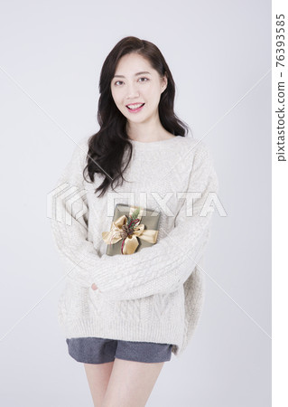 Asian female model with long hair holding gift, winter beauty concept Asian female model with long hair holding gift, winter beauty concept 76393585