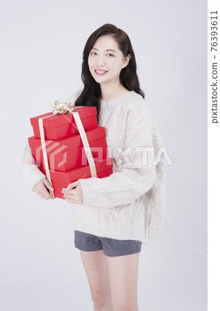 Asian female model with long hair holding gift, winter beauty concept Asian female model with long hair holding gift, winter beauty concept 76393611