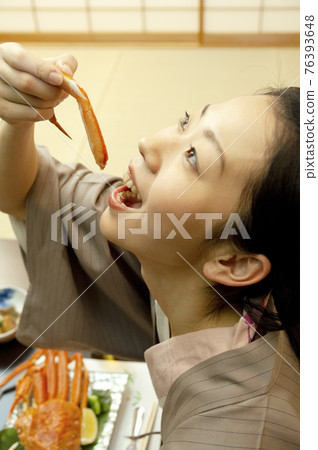 A woman in a yukata trying to eat a crab A woman in a yukata trying to eat a crab 76393648
