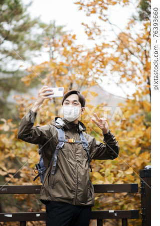 Asian handsome man with mask trekking, climbing autumn mountain Asian handsome man with mask trekking, climbing autumn mountain 76393660