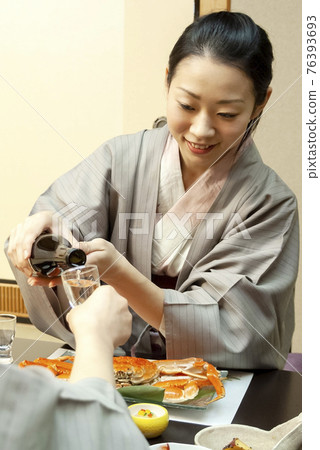 A woman in a yukata drinking a drink at an inn A woman in a yukata drinking a drink at an inn 76393693