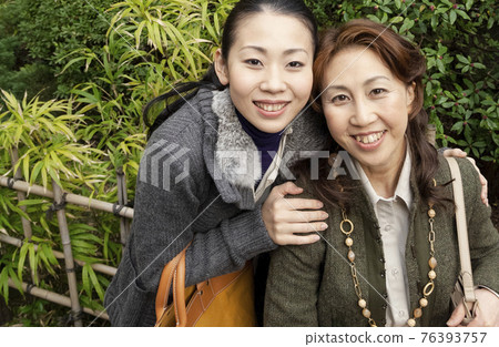 Mother and daughter cuddling with a smile 76393757