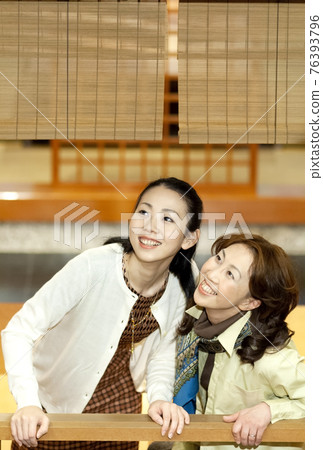 Mother and daughter looking up with a smile Mother and daughter looking up with a smile 76393796