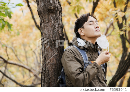 Asian handsome man with mask trekking, climbing autumn mountain Asian handsome man with mask trekking, climbing autumn mountain 76393941