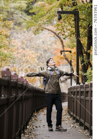 Asian handsome man trekking, climbing autumn mountain Asian handsome man trekking, climbing autumn mountain 76393961
