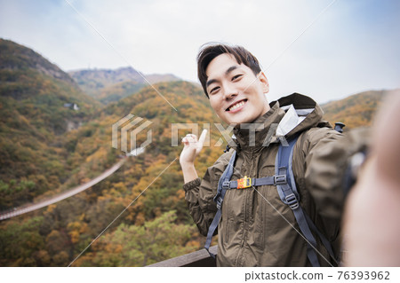 Asian handsome man trekking, climbing autumn mountain Asian handsome man trekking, climbing autumn mountain 76393962