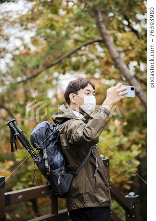 Asian handsome man with mask trekking, climbing autumn mountain Asian handsome man with mask trekking, climbing autumn mountain 76393980